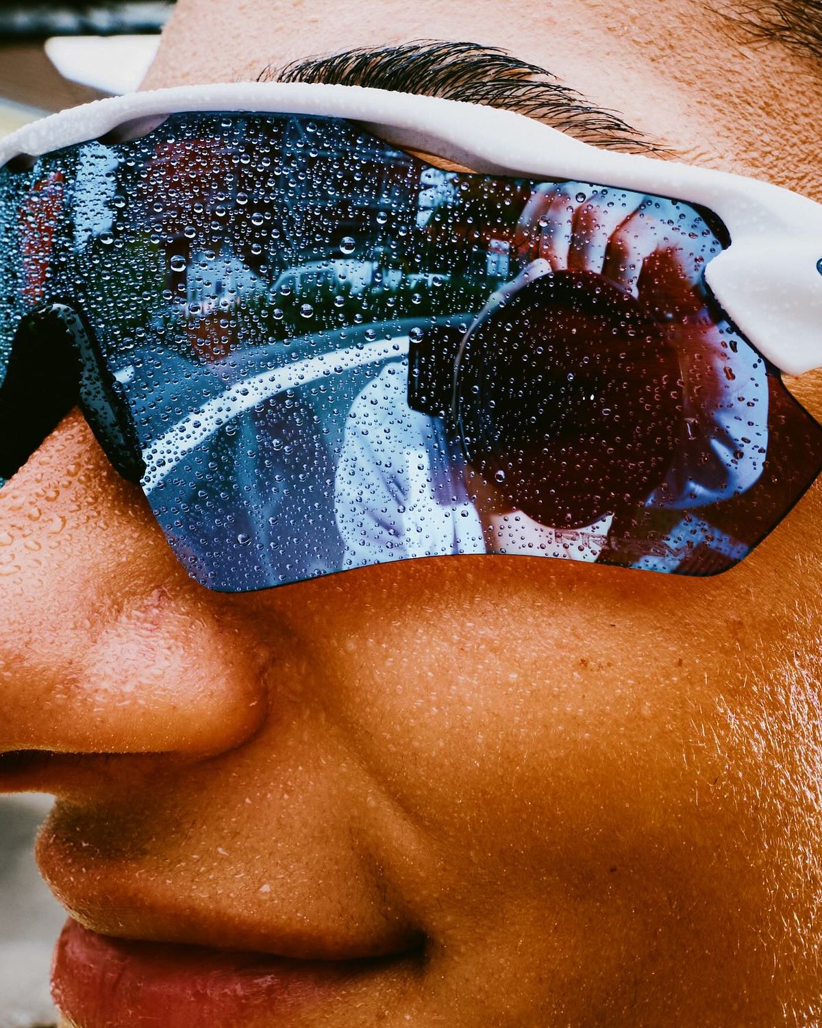 Close-up of a runner&rsquo;s face, sweat beaded across her sunglasses